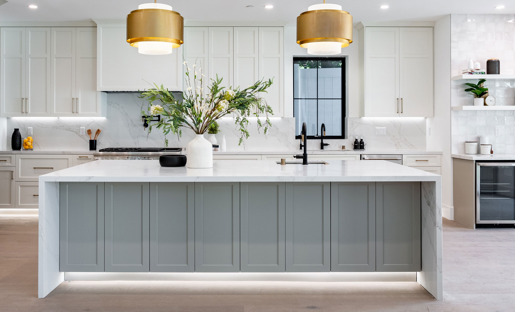 This kitchen has white cabinets and a large island with a white quartz countertop